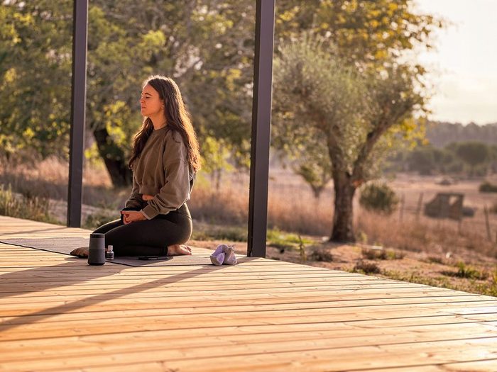 A quiet moment of meditation on a wooden terrace at Casas na Ferraria, surrounded by trees